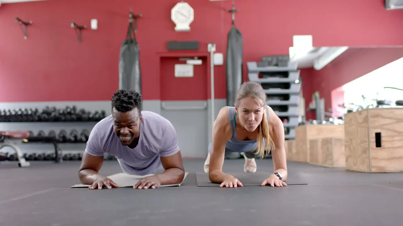 Fit diverse couple doing planks at the gym