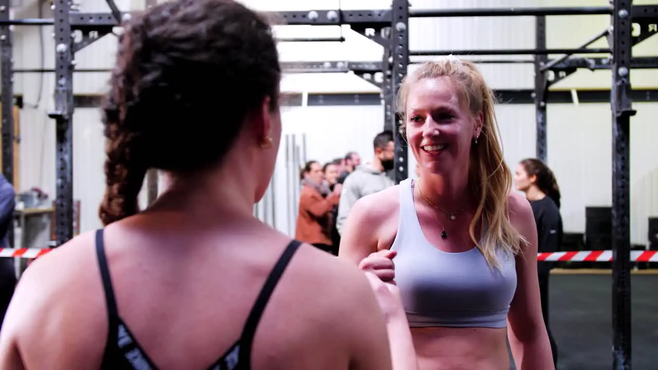 Beautiful Caucasian women in sportswear greet each other in crossfit gym