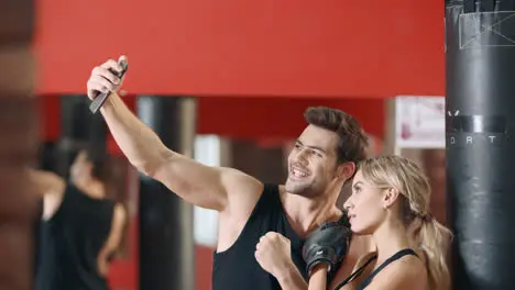 Fitness instructor doing mobile selfie with woman boxer after training