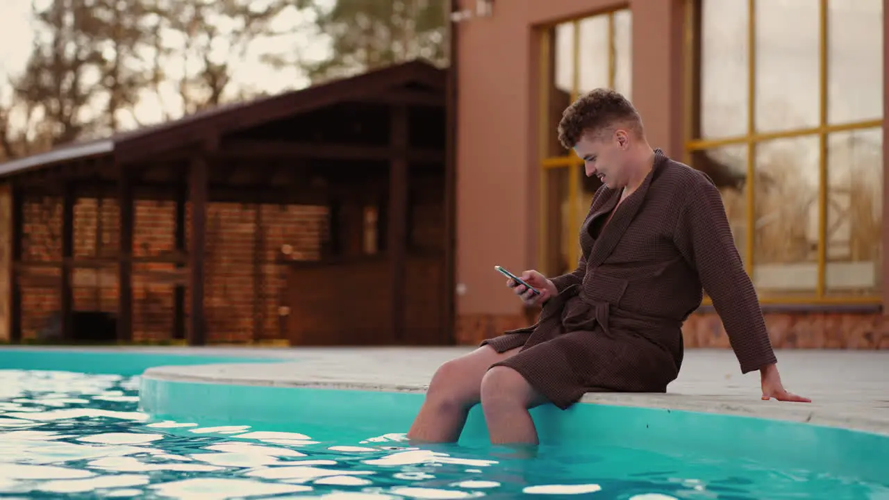 Ein Entspannter Mann Ruht Sich Im Freibad Eines Parks Aus Und Surft Mit Einem Modernen Smartphone In Den Sozialen Medien