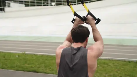 Active guy working out with fitness rope Man training outdoor at sport stadium