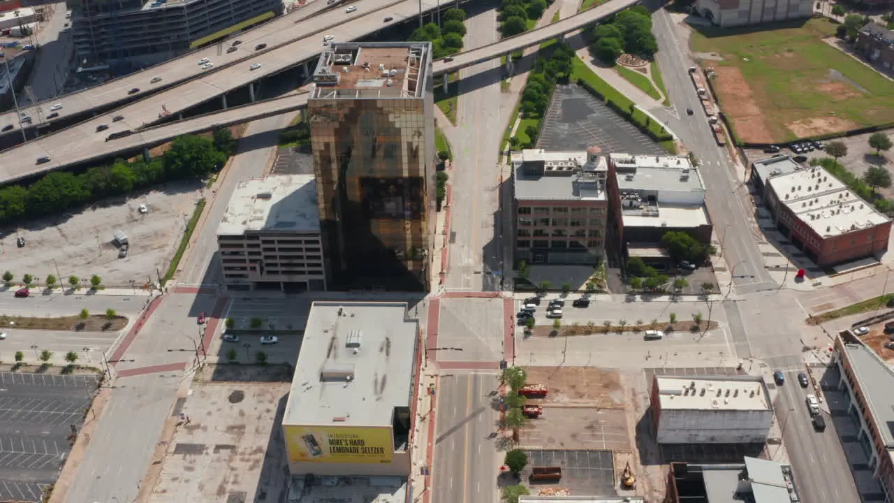 Aerial view of various buildings along highway Forward flying drone tilt down footage of multi-storey commercial property with glass facade Dallas Texas US