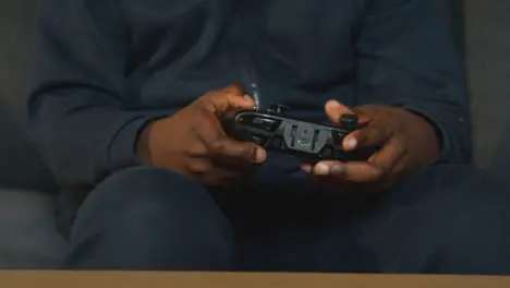 Close Up Boy Holding Controller At Home Sitting On Sofa Playing Video Game 