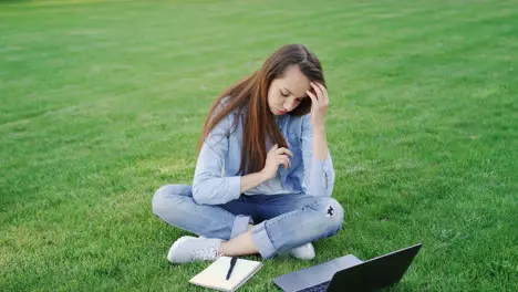 Thoughtful woman study online on laptop computer in summer park