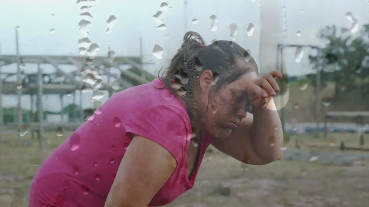 Animation of water droplets over tired caucasian woman wiping brow at bootcamp training course