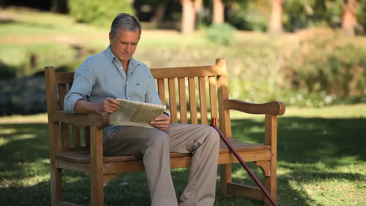 Senior man reading a book sitting on a bench