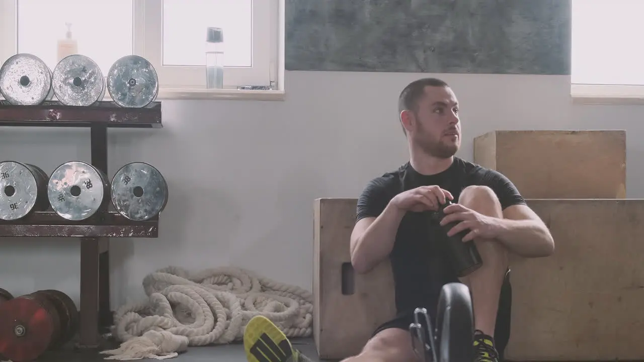 A Young Man Dries His Sweat And Drinks Water After Exercising In The Gym