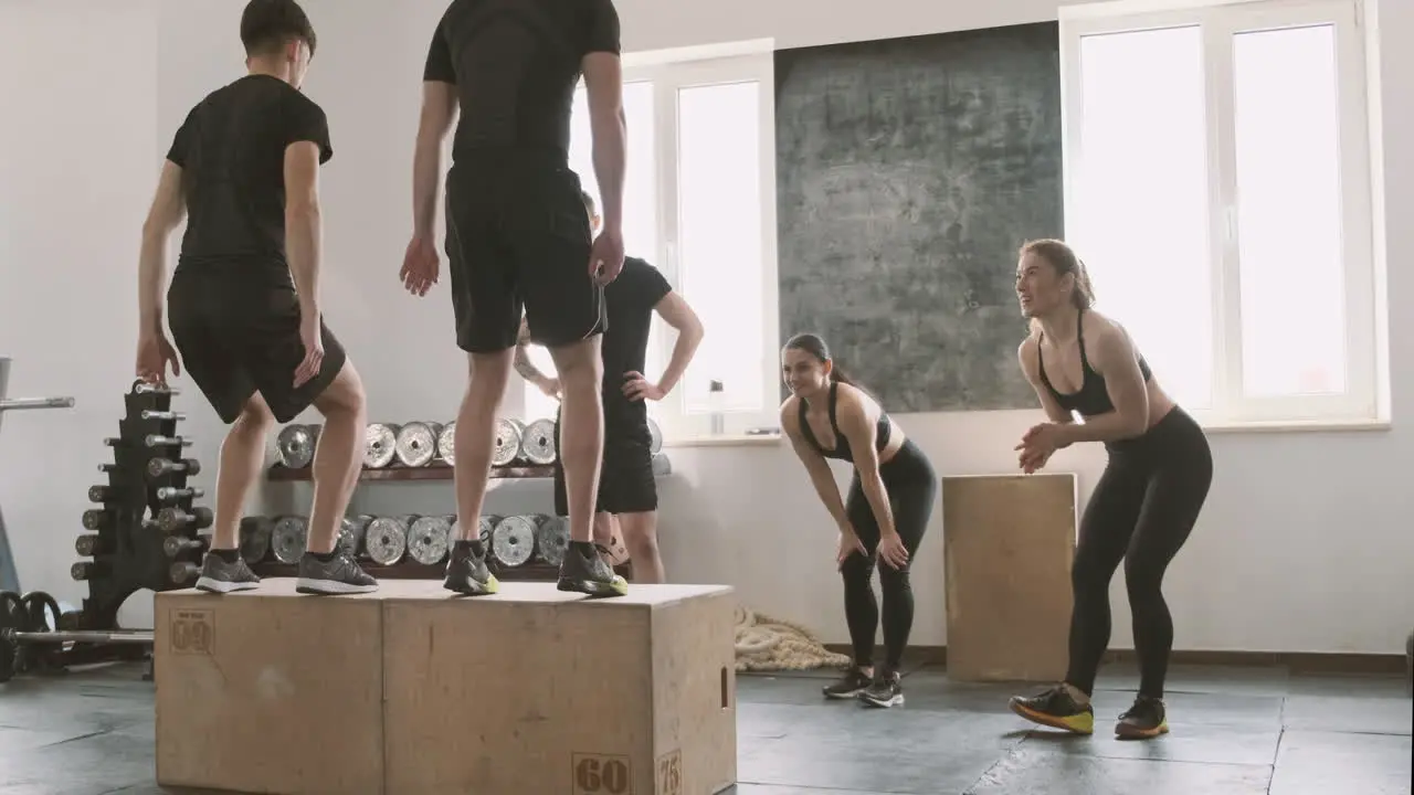 Two Young Men Jumping The Boxes While Their Gym Buddies Support Them