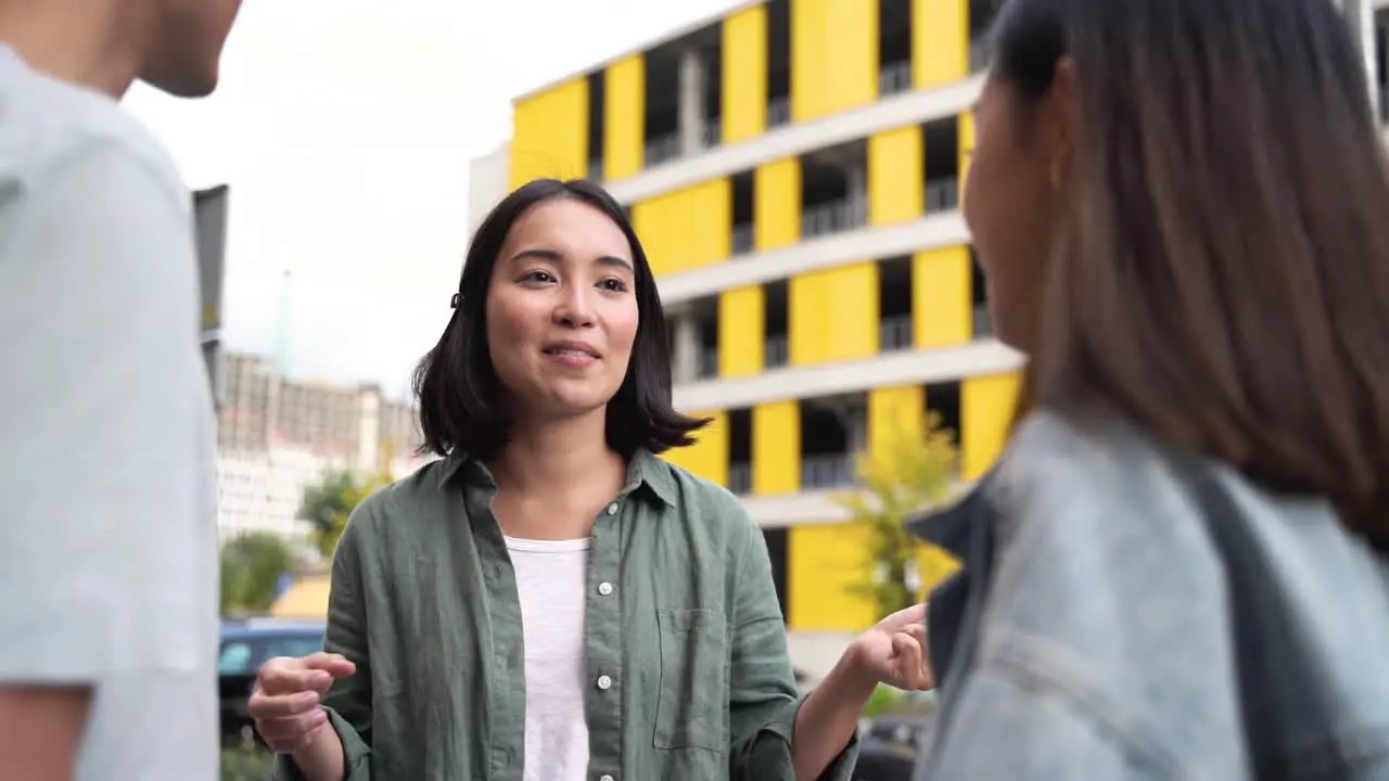 Pretty Young Japanese Woman Talking To Her Two Friends While Standing Together Outdoors In The Street