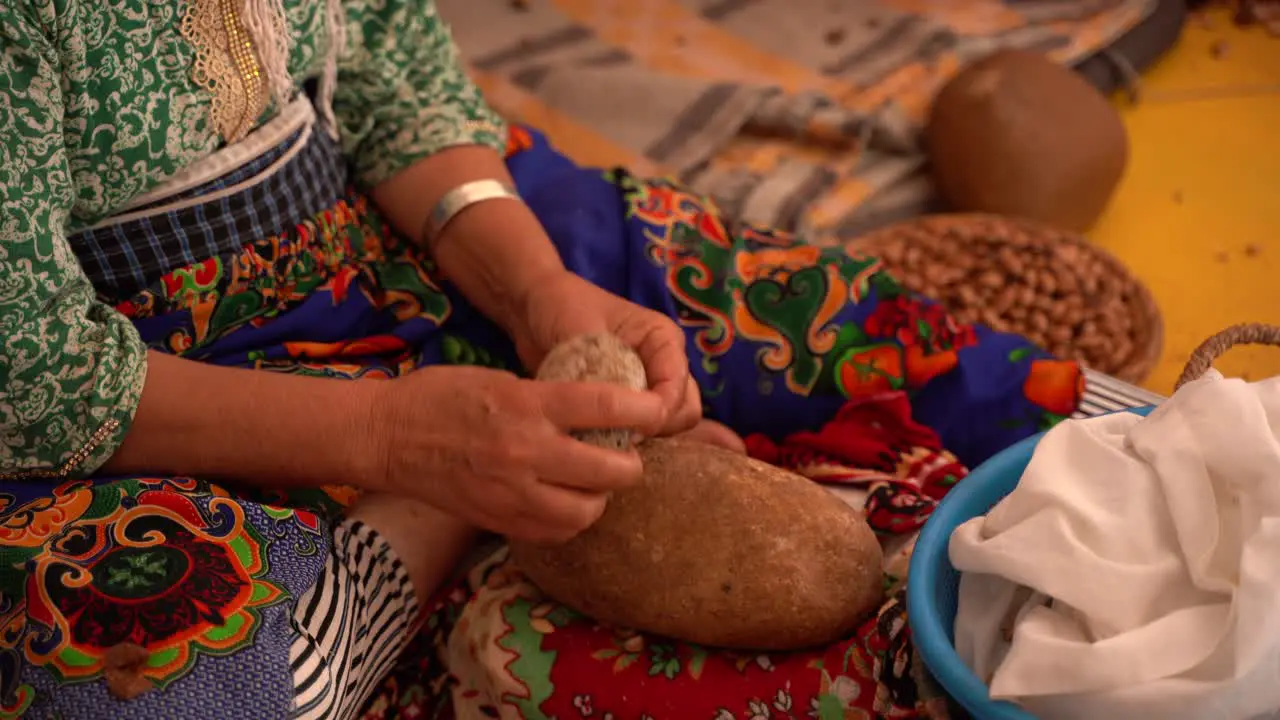 A woman destroying the seeds used to produce the argan oil Morocco