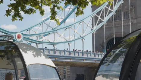 Crowd Of Summer Tourists Walking By Tower Bridge London England UK With Restaurant Pods In Foreground 2