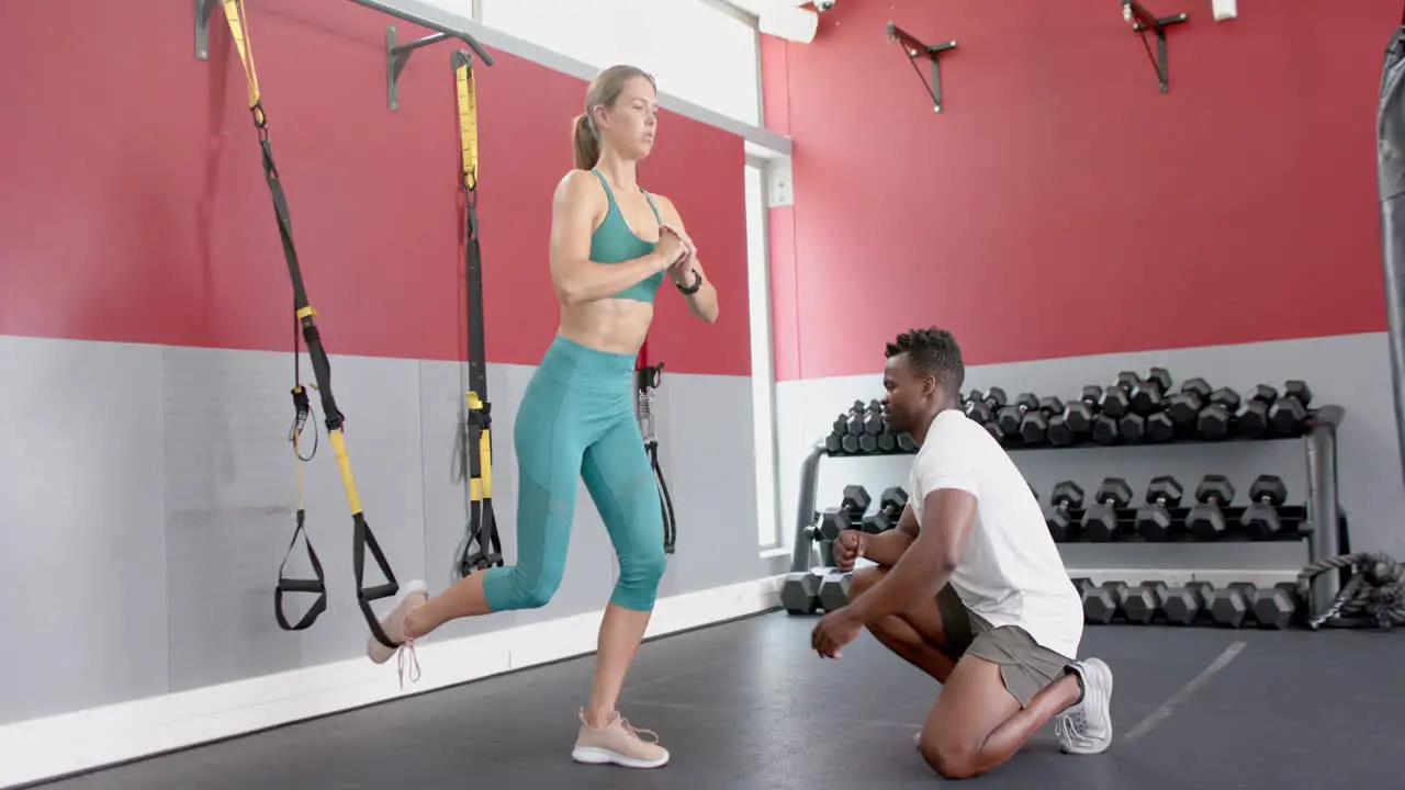 Fit young Caucasian woman trains with an African American man at the gym