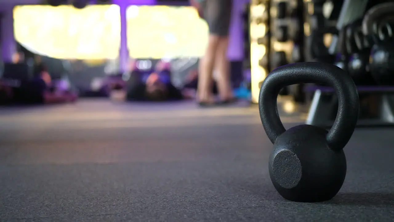 A kettlebell weight in a gym with people working out in a fitness training class in the background