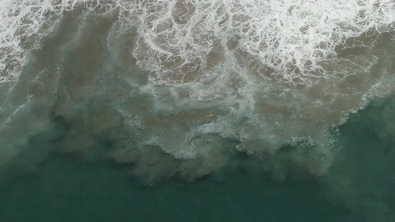 Wave action near shore stirs up clouds of sand in ocean water abstract