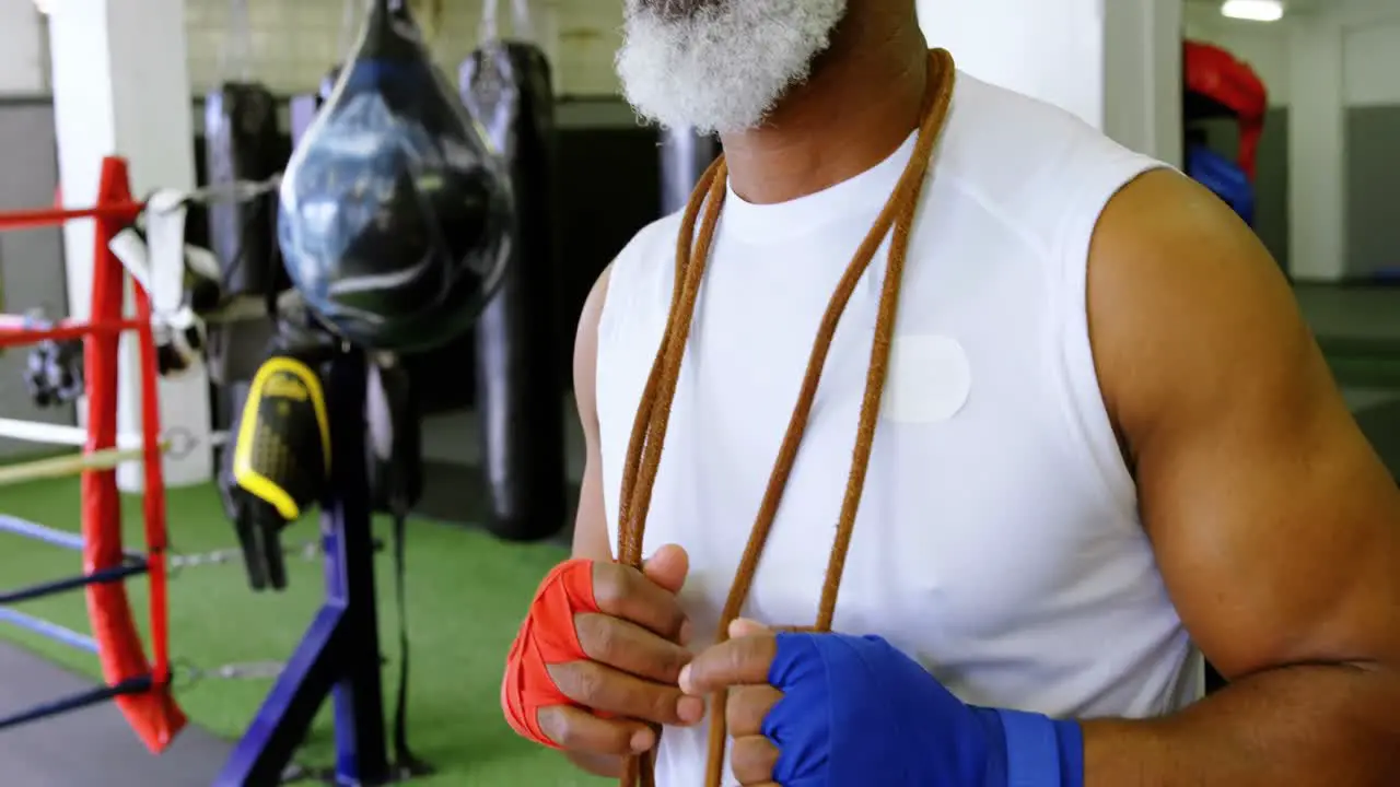 Senior man standing with skipping rope in fitness studio 4k