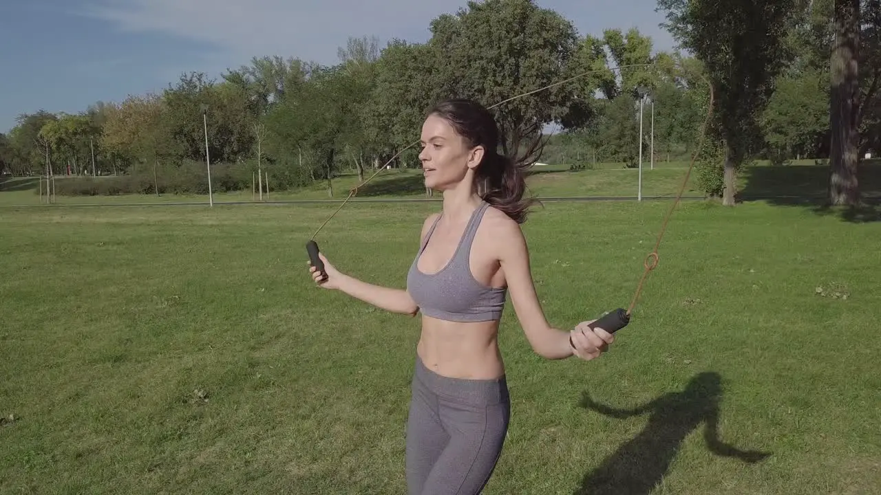 Beautiful smiling young girl jumping rope in nature