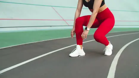 Sport woman lacing up sneakers for workout on track Woman runner tying up shoes