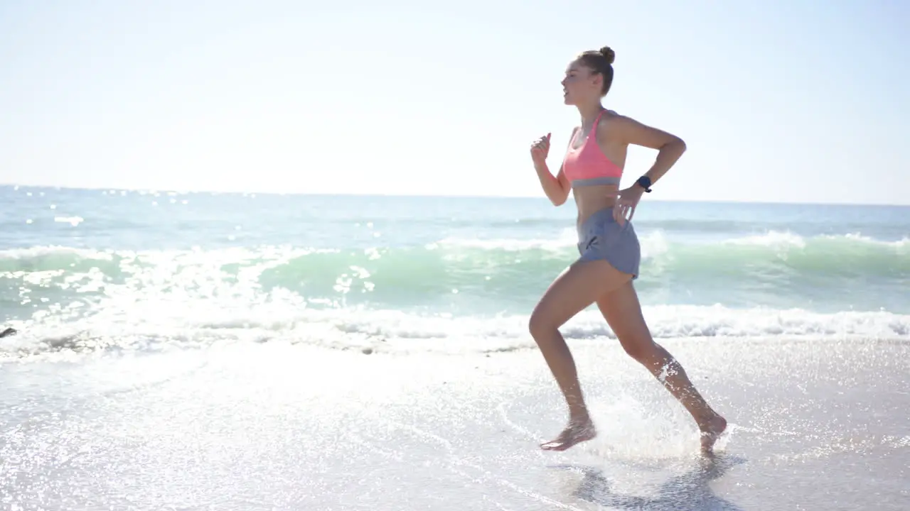 Young Caucasian woman jogs along the shoreline with copy space