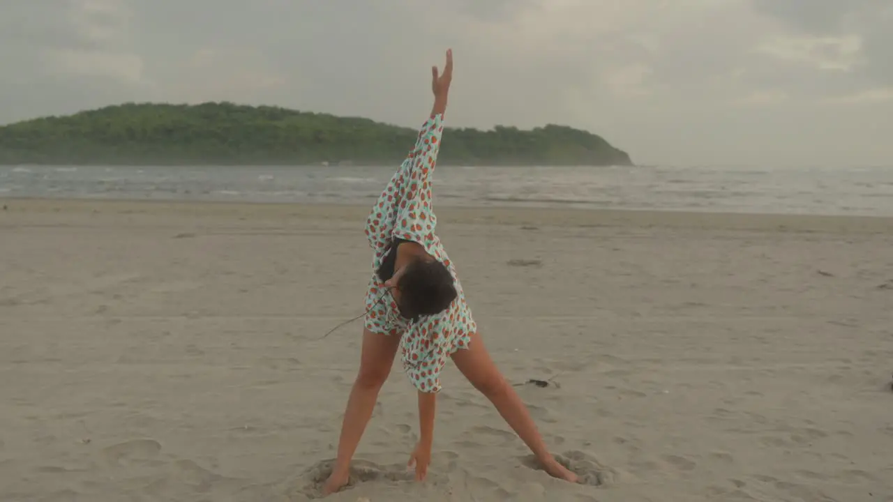 A woman gracefully performs yoga poses on the serene beach