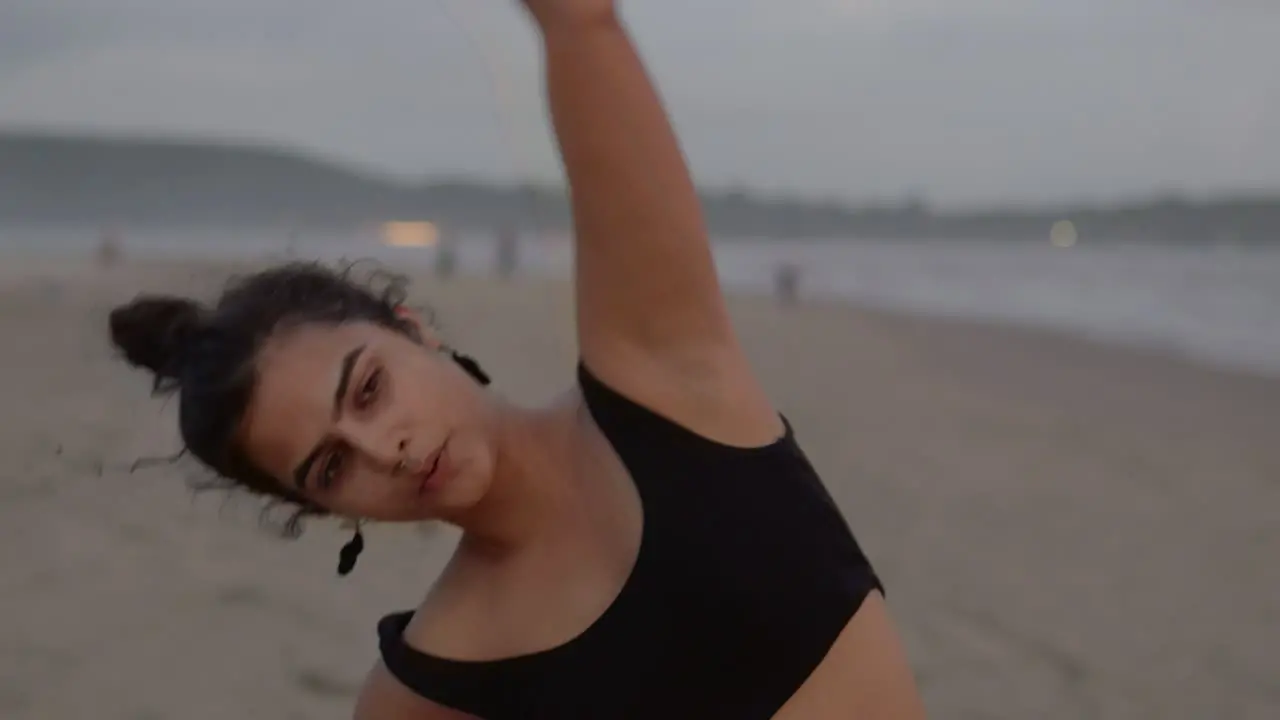 A close-up shot captures an Indian woman focused on her fitness routine at the beach