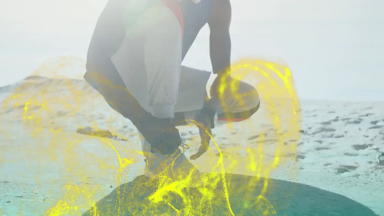 Golden digital wave against african american fit man tying his shoe laces at the beach