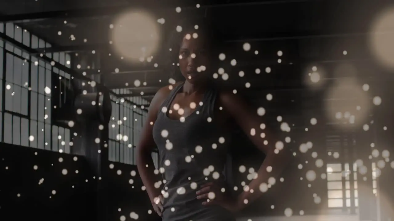 Digital composite video of yellow particles floating against portrait of african american woman