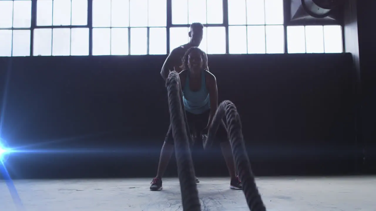 Blue spot of light against african american woman training with battle rope