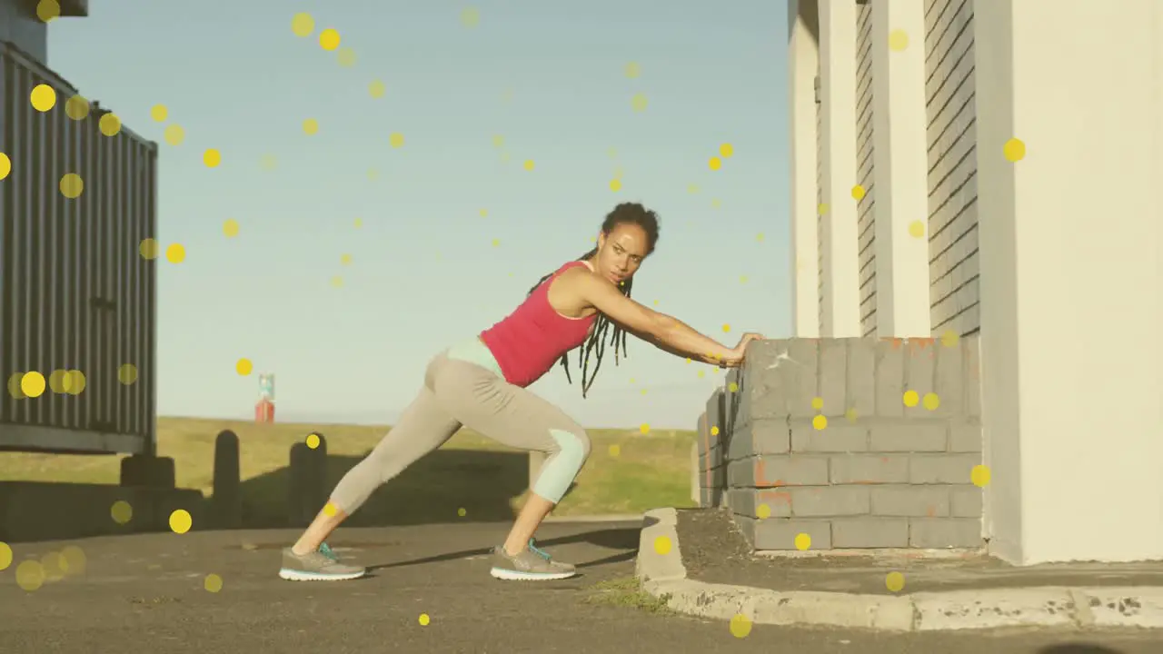 Multiple yellow spots floating against african american fit woman performing stretching exercise