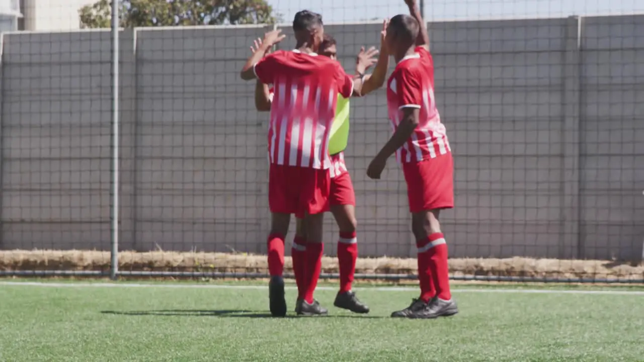 Animation of social media icons over team of diverse male soccer players celebrating on sports field