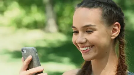 Cheerful woman using mobile phone while morning run in summer park