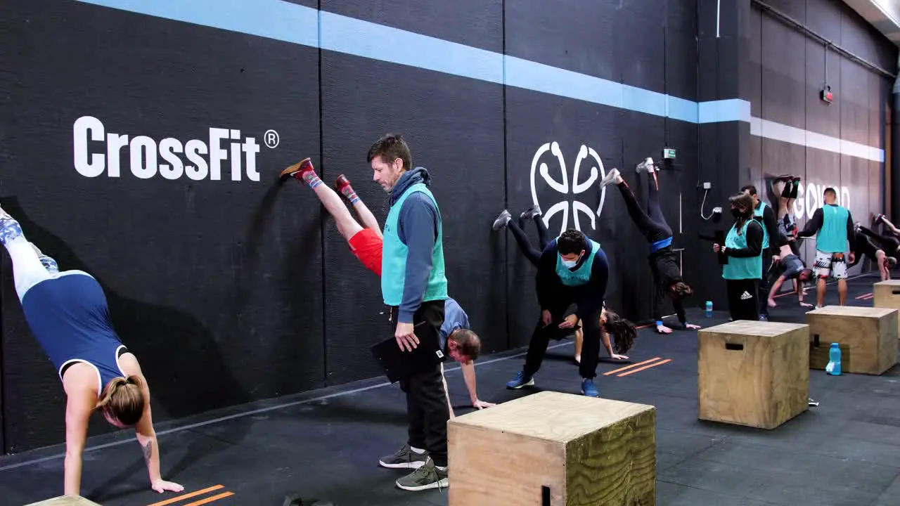 People doing a crossfit challenge with a coach competing to each other while doing exercises in open gym