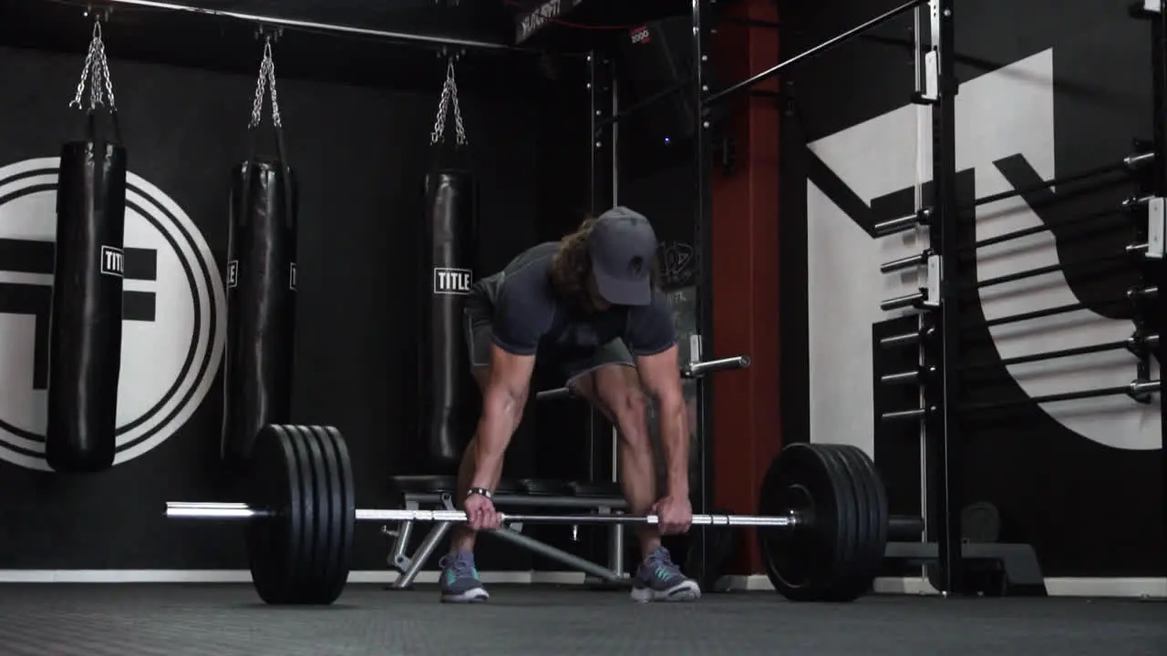 Muscular man doing heavy dead lifts with heavy weight in a dark gym