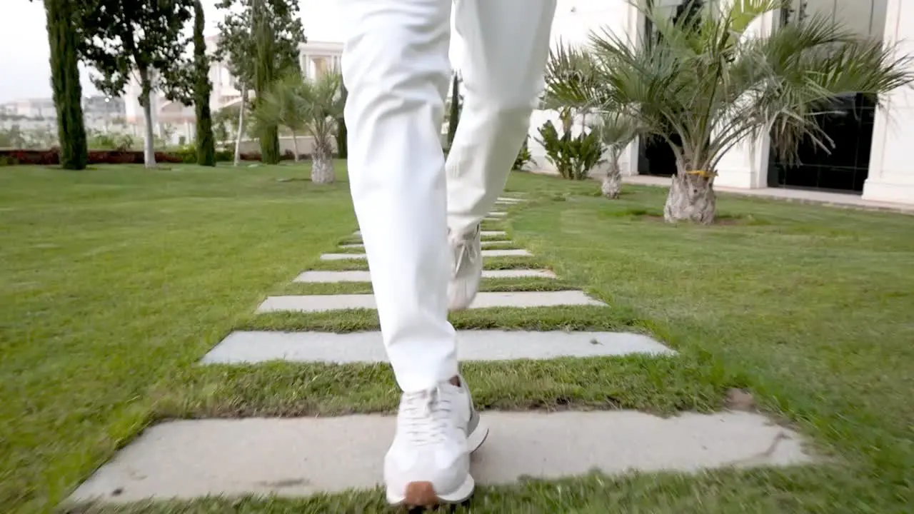 Detail of man legs with sport clothes running on pavement with grass