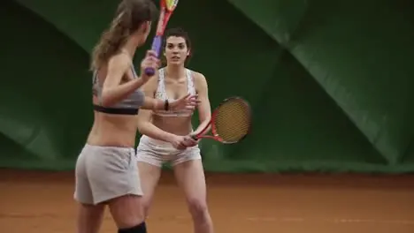 The female tennis coach shows the technique of rack with racket to a beautiful long haired girl on the tennis court Slow motion