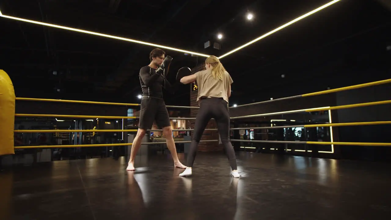 Serious fit girl fighting with coach at gym Sport couple training in sport club