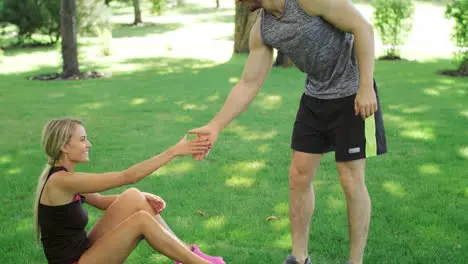 Athlete man help young woman stand up from green lawn Sport people teamwork