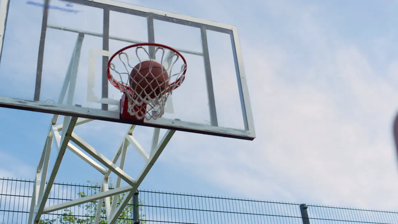 Focused sporty woman practicing street basketball with man in playground