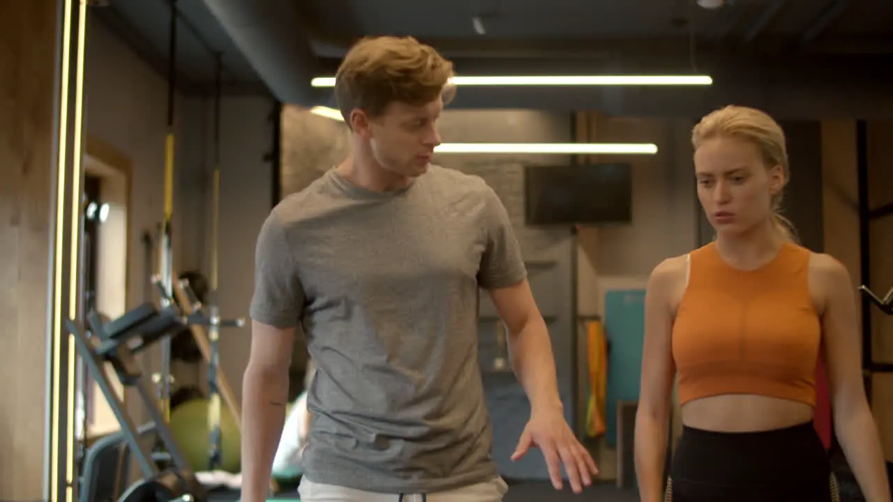 Cheerful fit couple walking at gym Sport man and woman talking in sport club