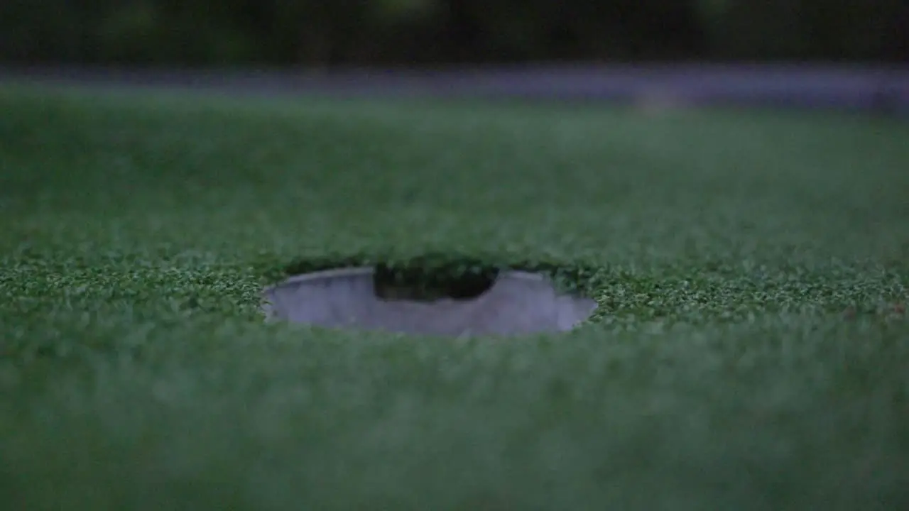 Golf ball rolling into hole in slow motion