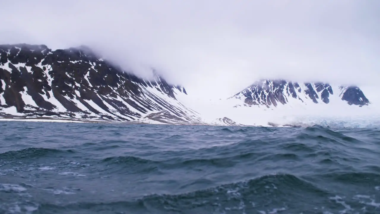 Sailing across a glacier and snow capped mountains on a yacht in the Arctic