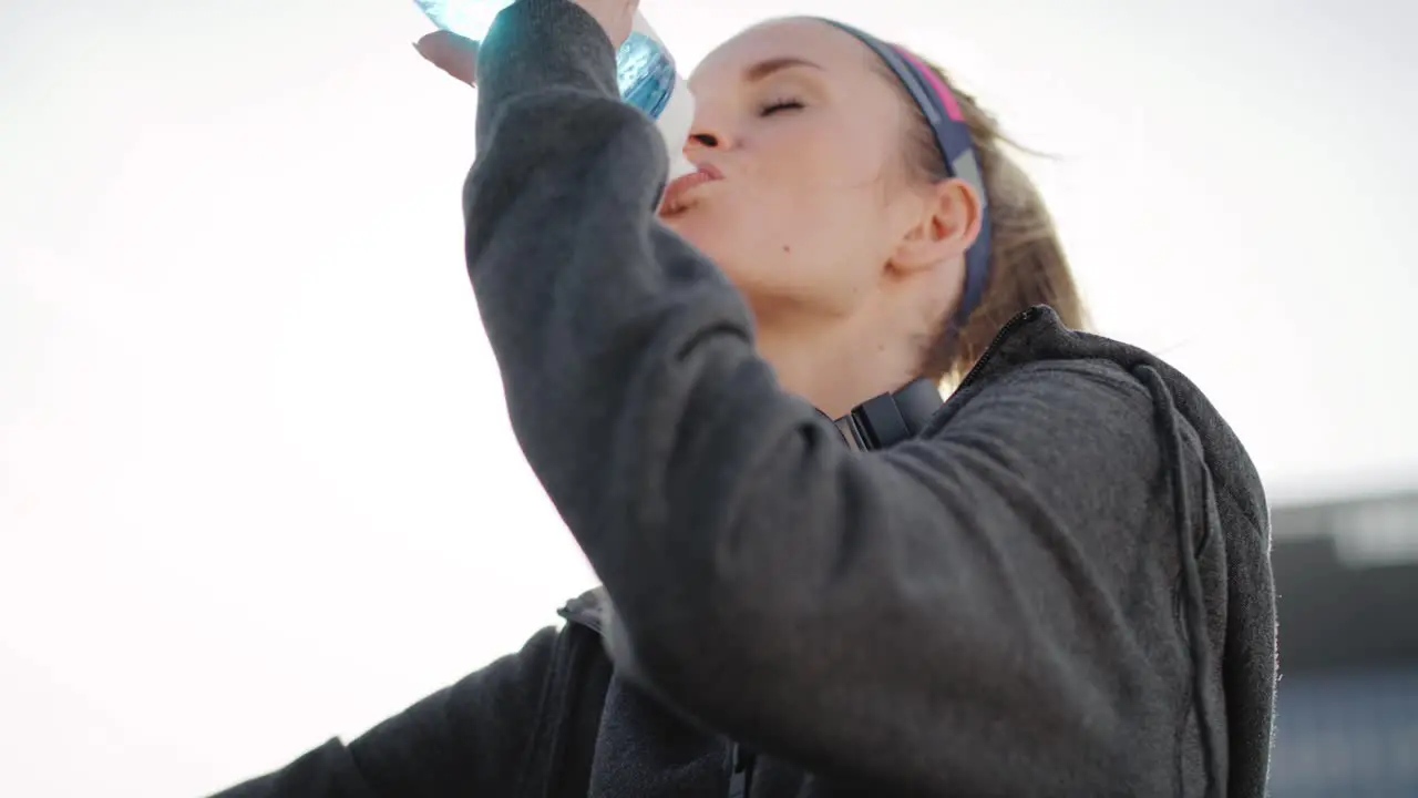 Tilt up video shows of sporty woman drinking water