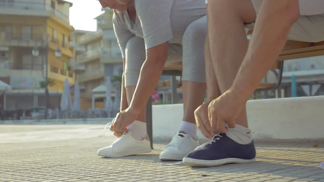 Senior man and woman lacing shoes before training