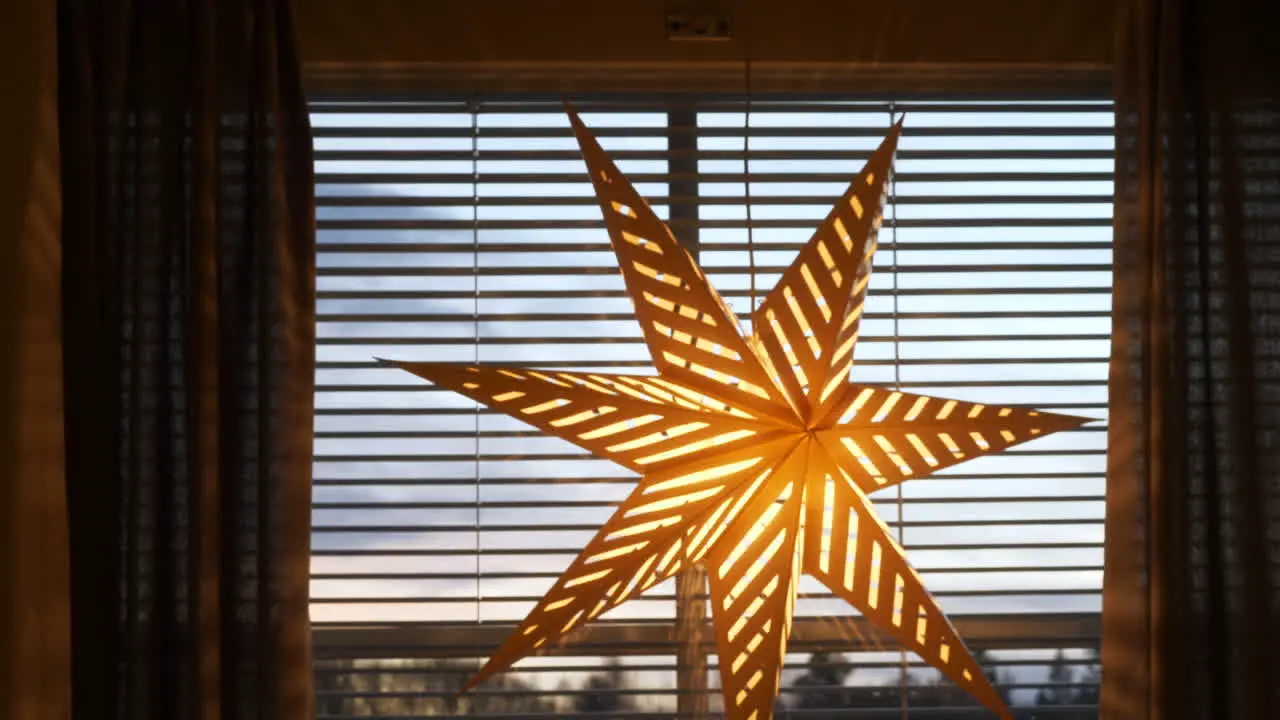 Christmas star ornament brightly lit in window medium shot