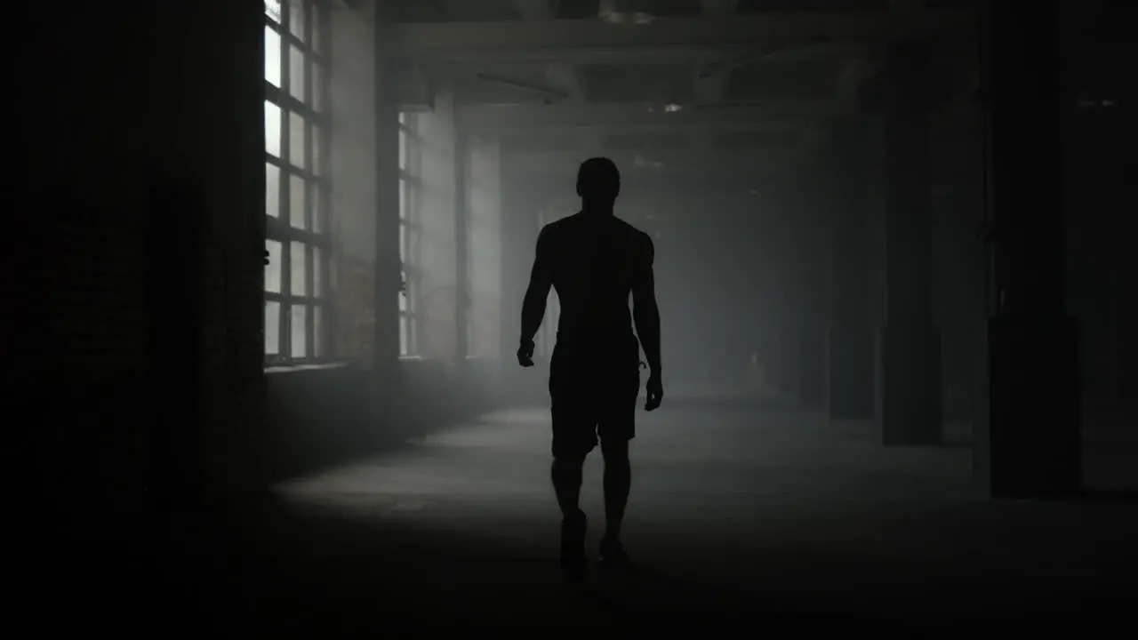 Man silhouette walking in dark corridor Athlete taking break after workout