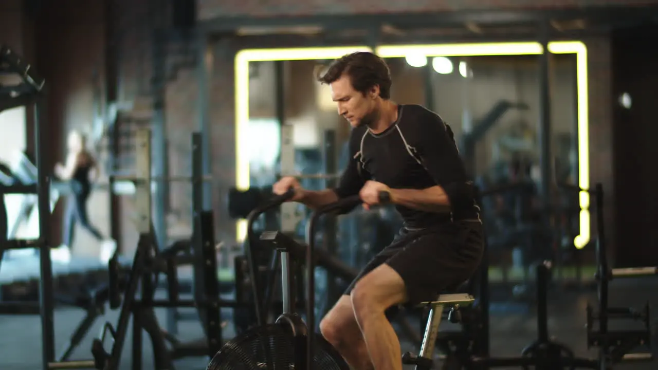 Eager athlete doing cardio in sport club Fit man training on exercycle at gym