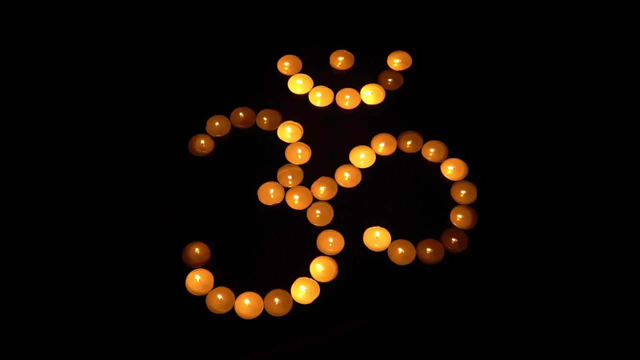 Om symbol from burning candles on black background for meditation and mantra