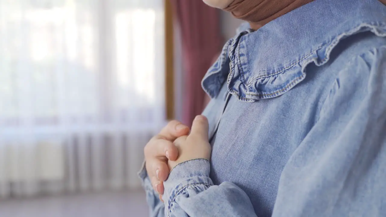 Muslim woman in hijab praying at home