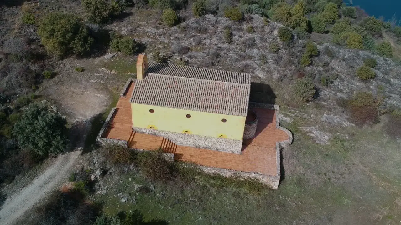 Aerial shot orbiting over a small hermitage near a lake