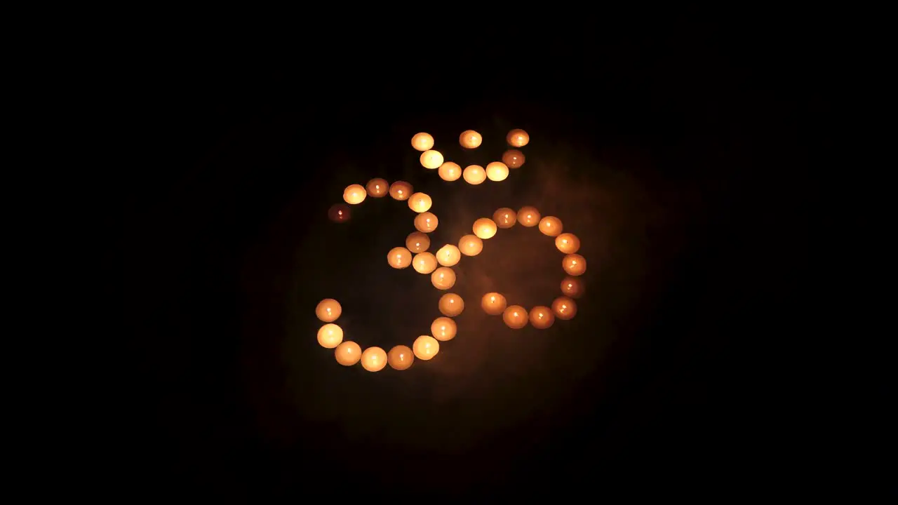 Om symbol from burning candles with smoke movement on black background