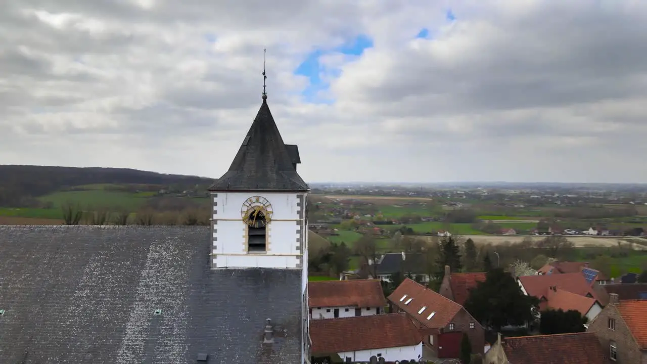 Aerial drone rotating around church clock with Belgian hills in the background